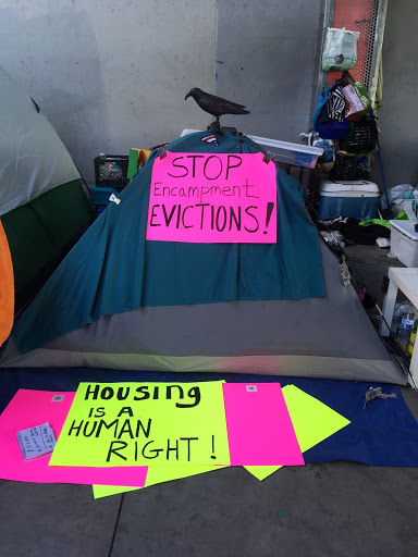 An image of a tent with the words "Housing is a Human Right"