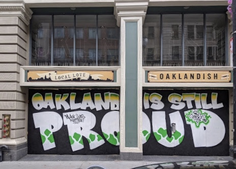 A mural says "Oakland is still proud" in big letters.