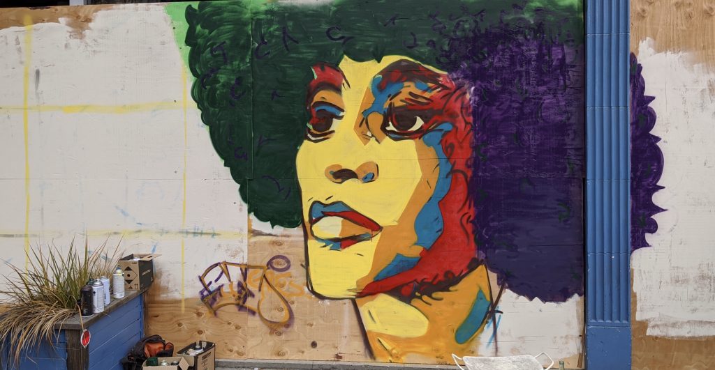 A mural of a black woman with an afro that is multihued.