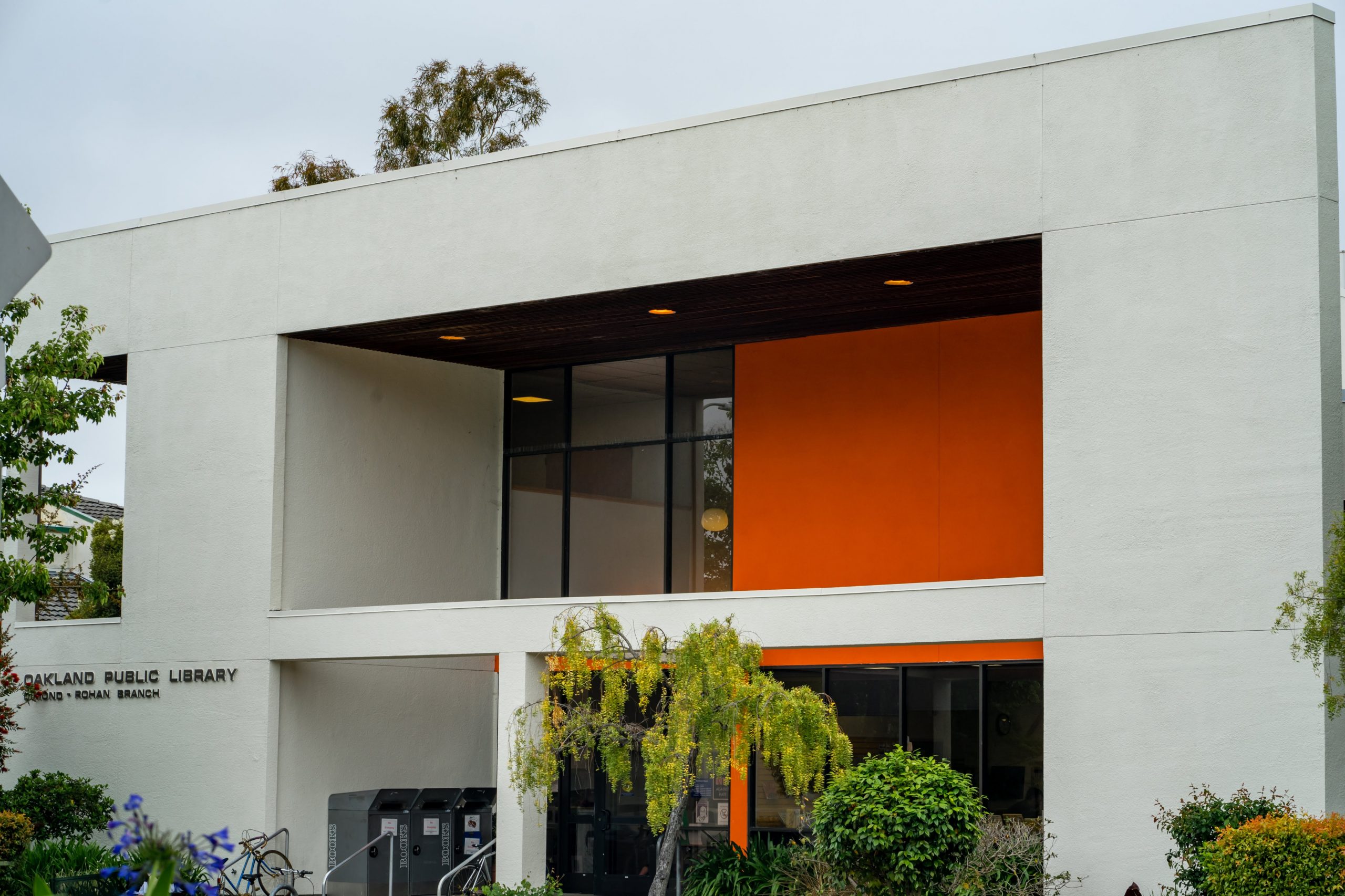 A image of the outside of a white and orange library in Oakland.
