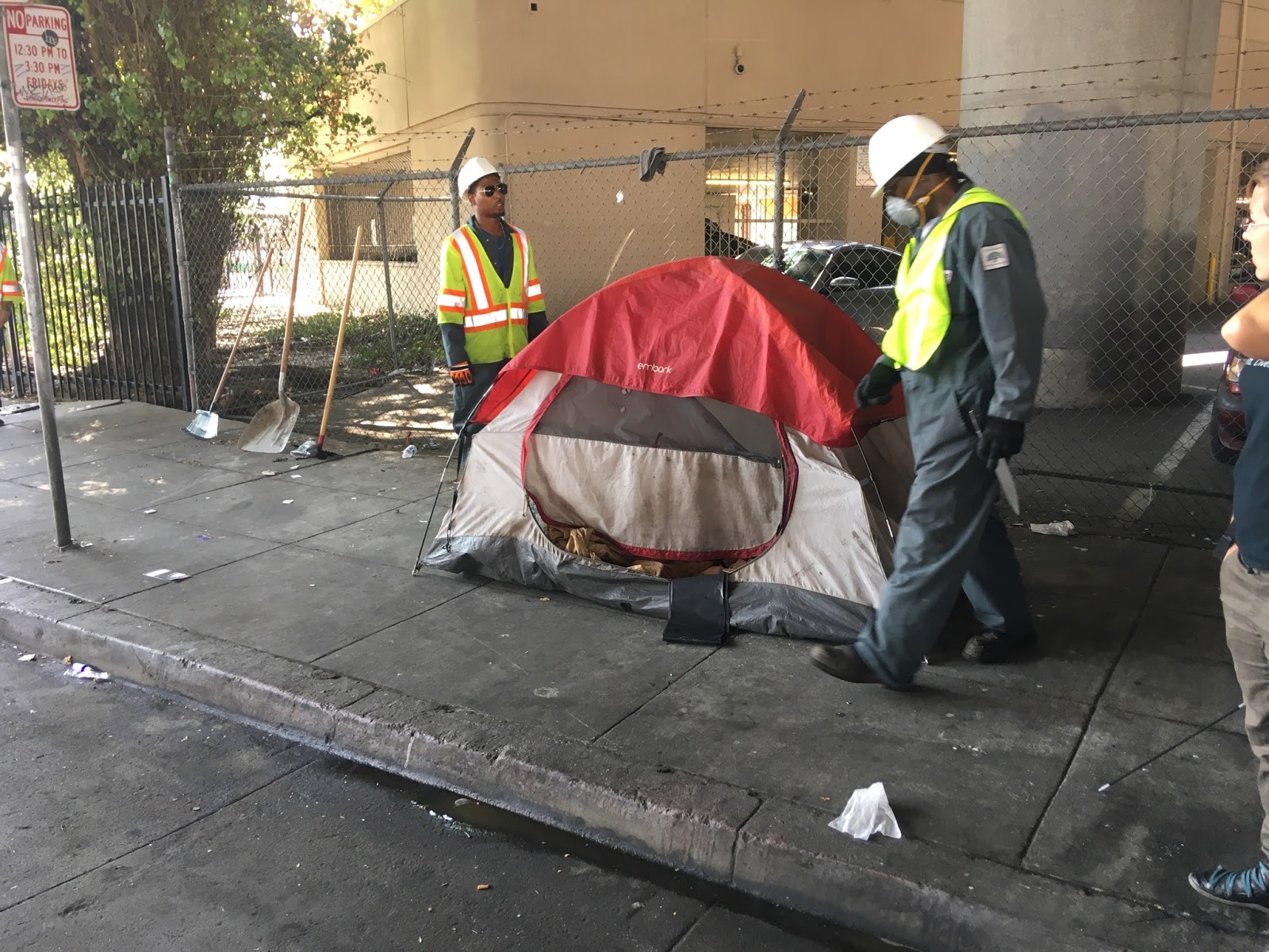 Two city workers remove a curbside tent.