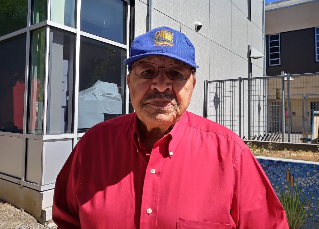 Ben Tapscott. Photo by Tony Daquipa. A man wearing a blue hat and red shirt looks at camera.
