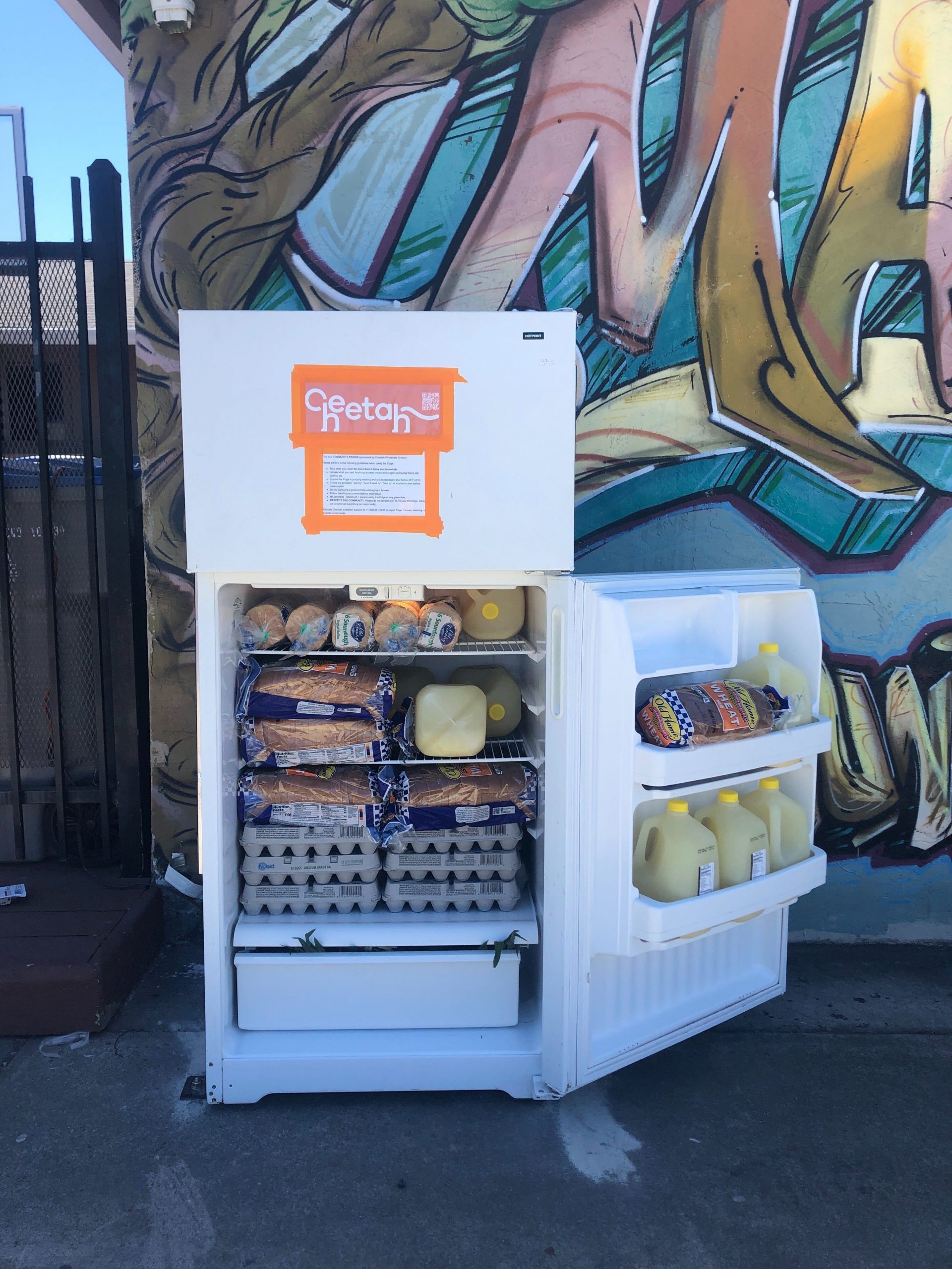 An open small refrigerator door with "Cheetah" in orange logo. The fridge has bread, juice, and eggs.