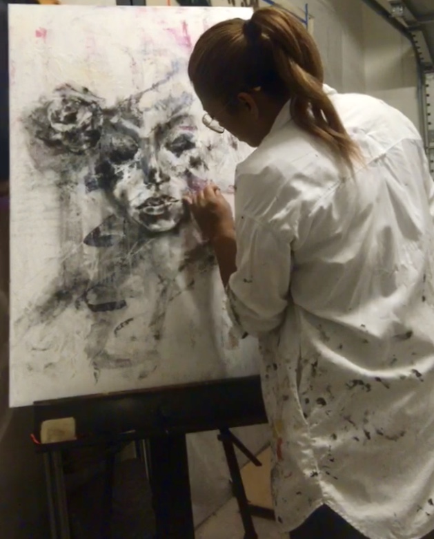 an artist in a ponytail works on a black and white drawing.