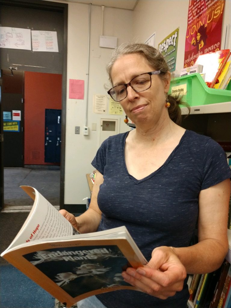 A woman with glasses is reading a book.