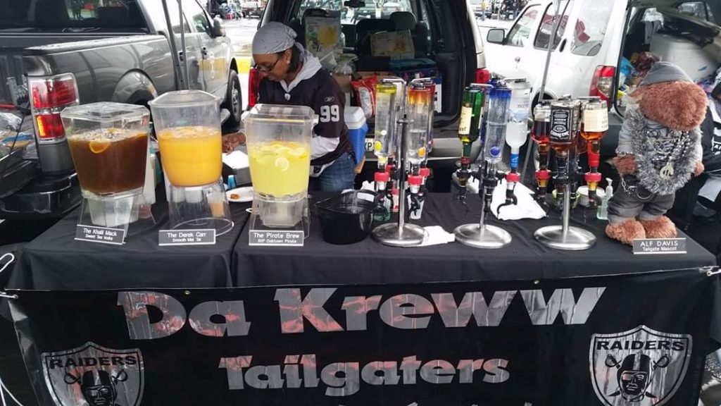 A close up photo of a makeshift tailgating bar with "Da Kreww" banner in front.