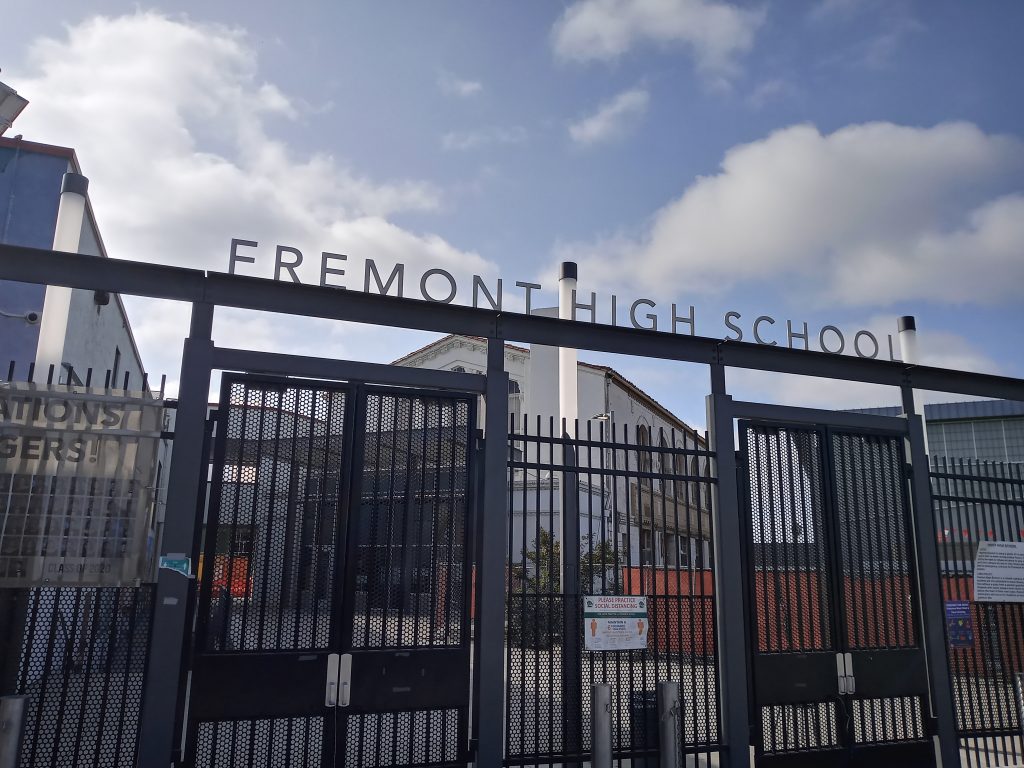 An image of a school with gates in the front and the words "Fremont High"