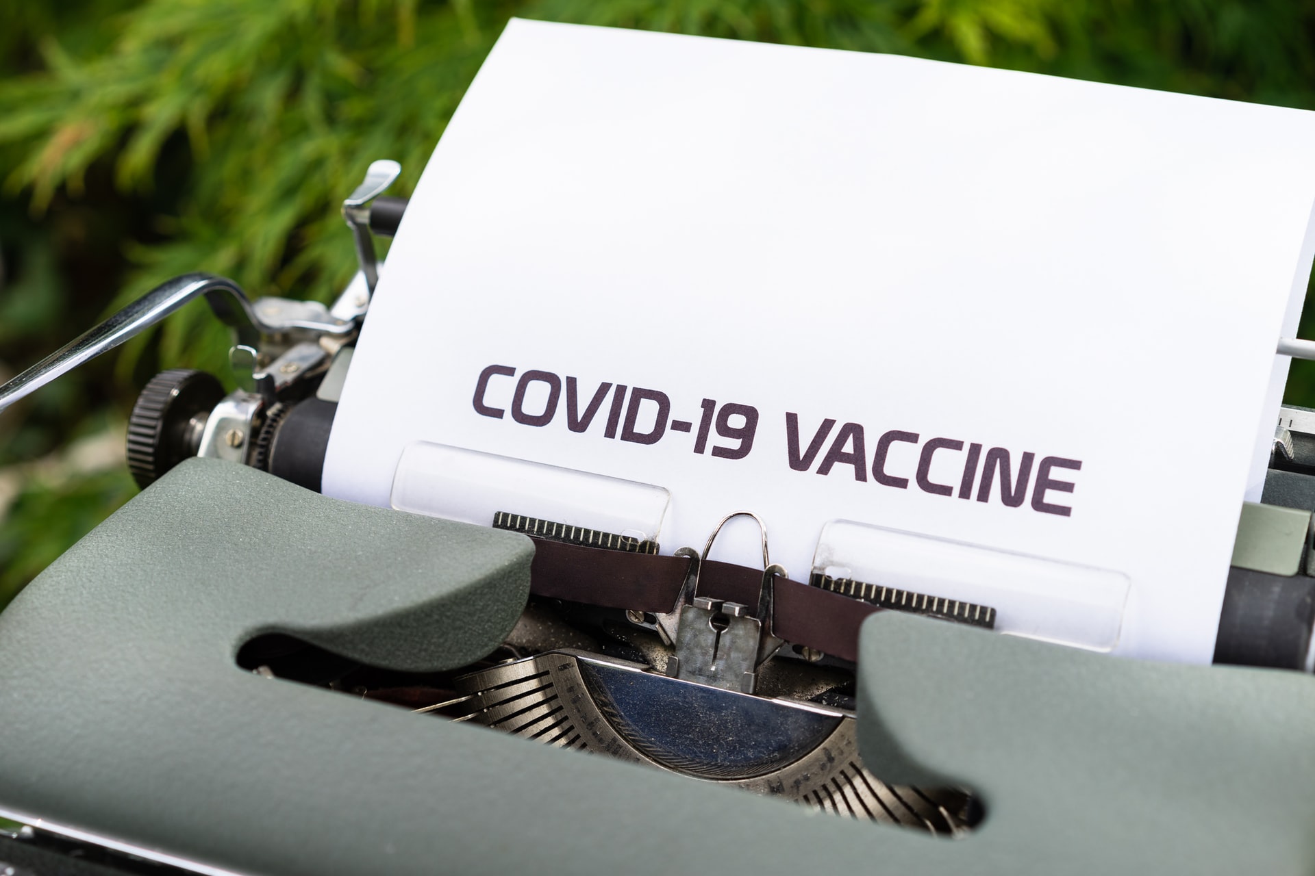 A typewriter with a paper that says "COVID-19 VACCINE"