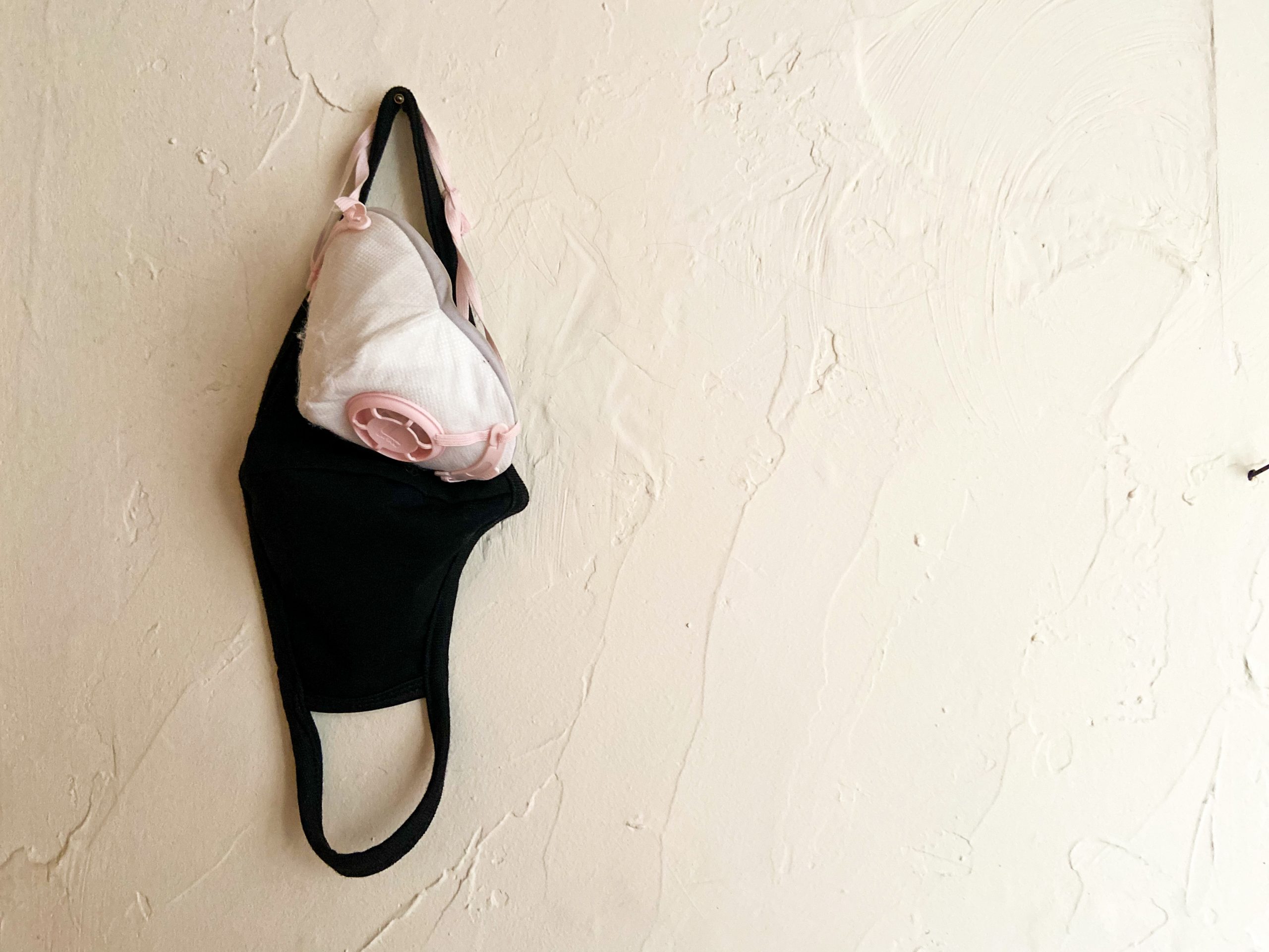 a white and black mask hang on a wall together
