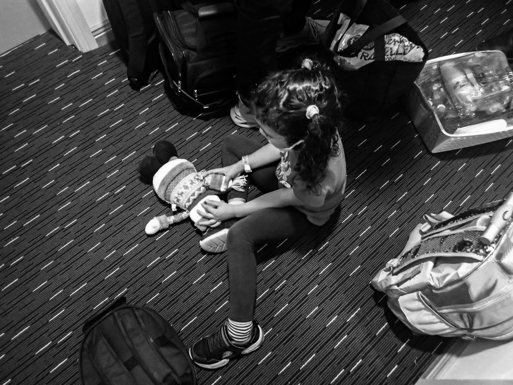 a black and white photo of young girl playing on the floor with a doll