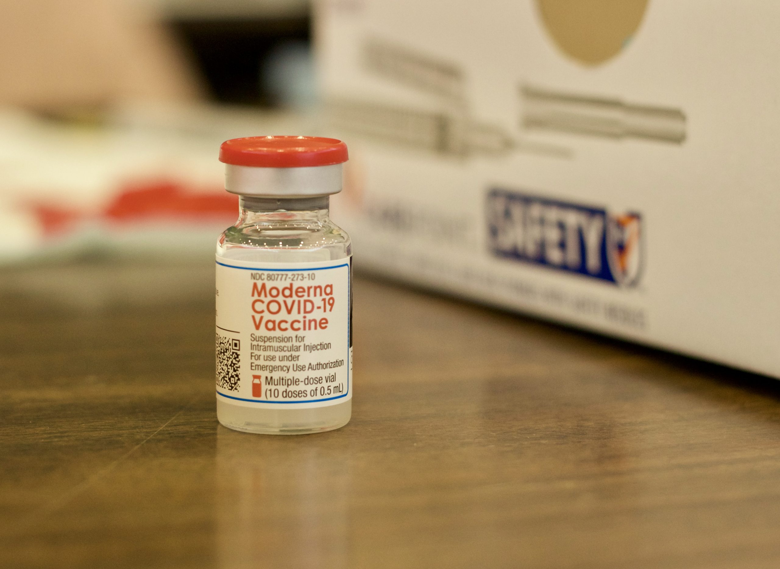 close up of a small vial of COVID vaccine with a red cap.
