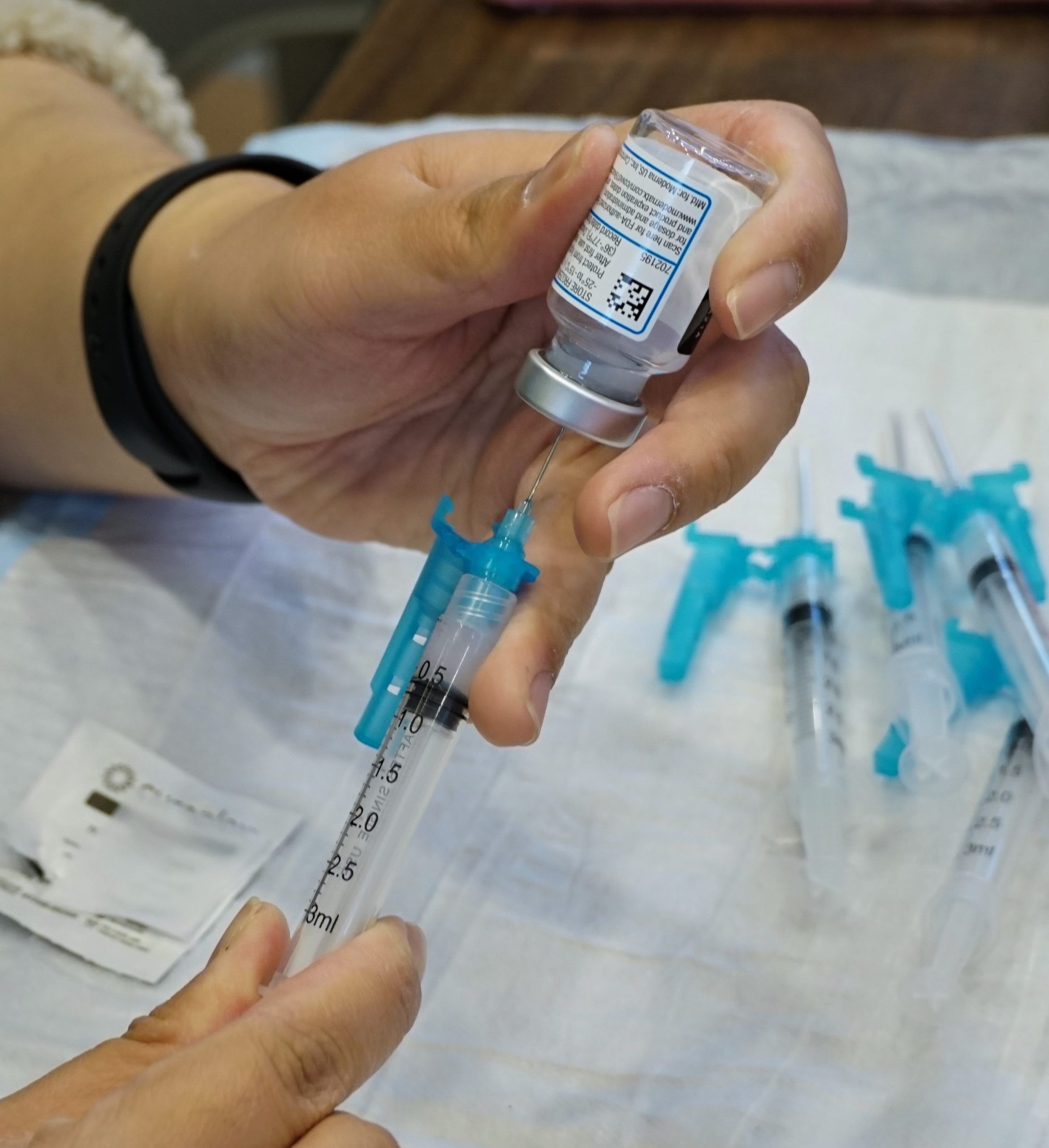 an upside down vial of the covid vaccine is put into a syringe