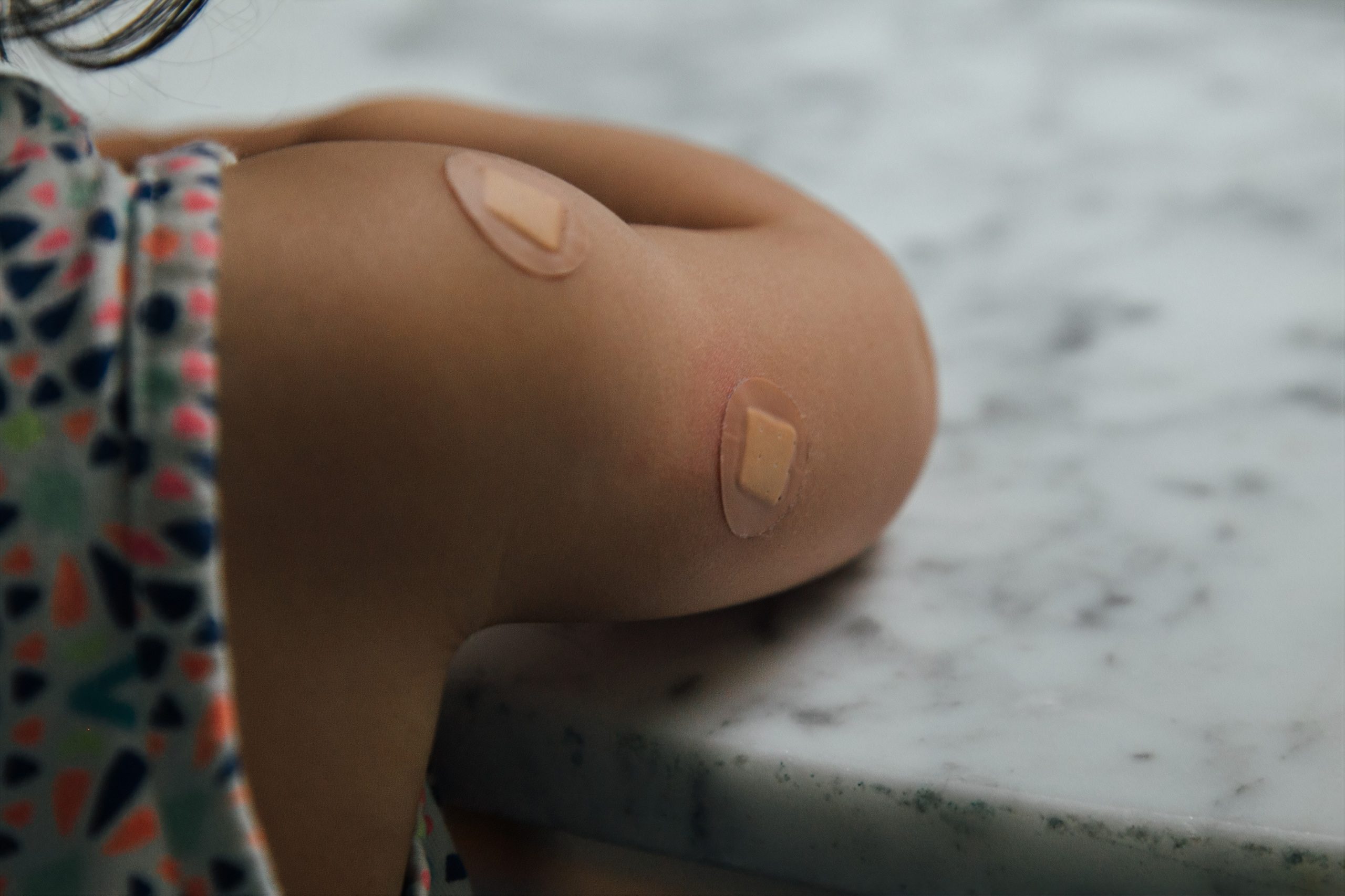a kid's arm with small bandaids to cover where they got a shot