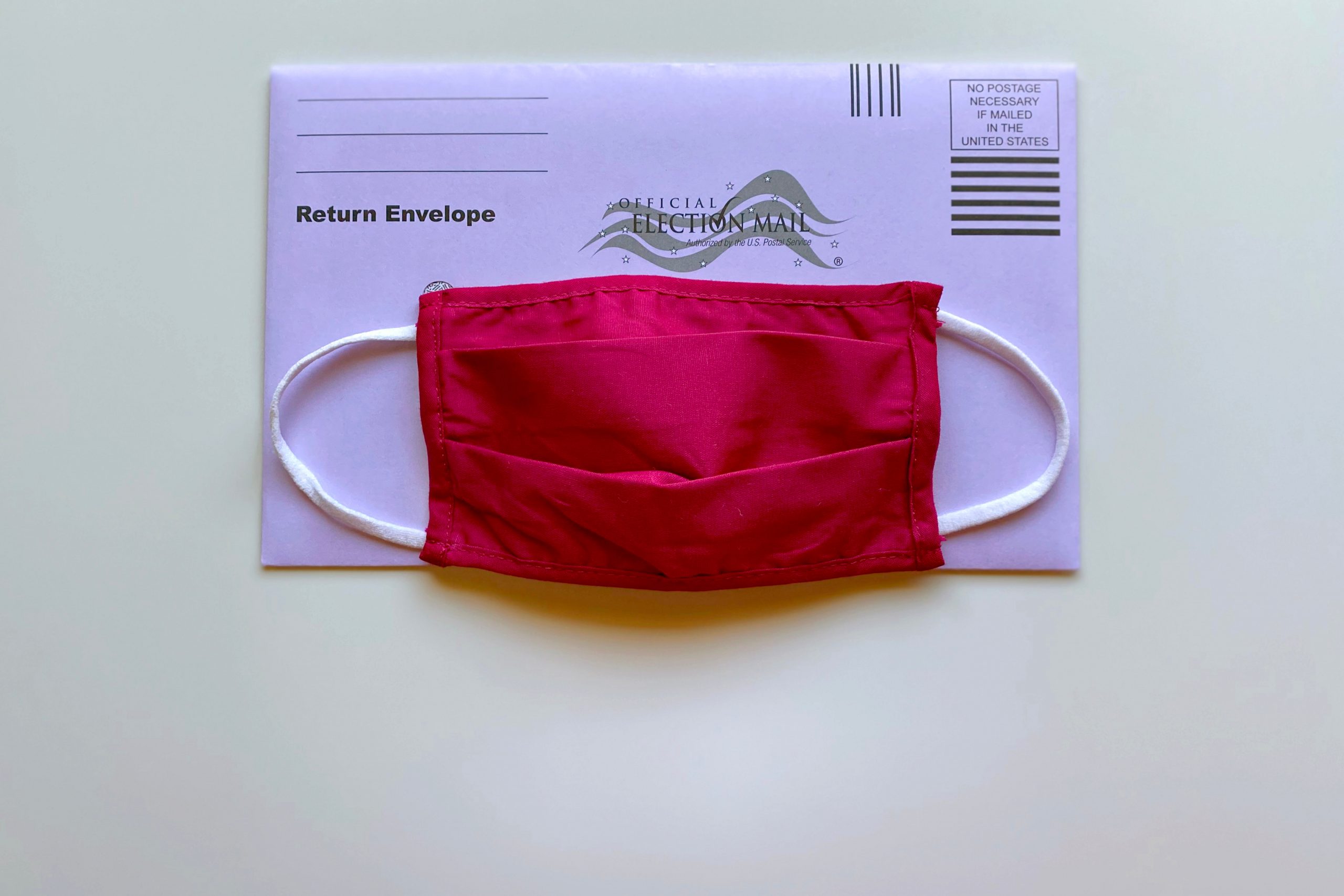 a red cloth face mask over a ballot