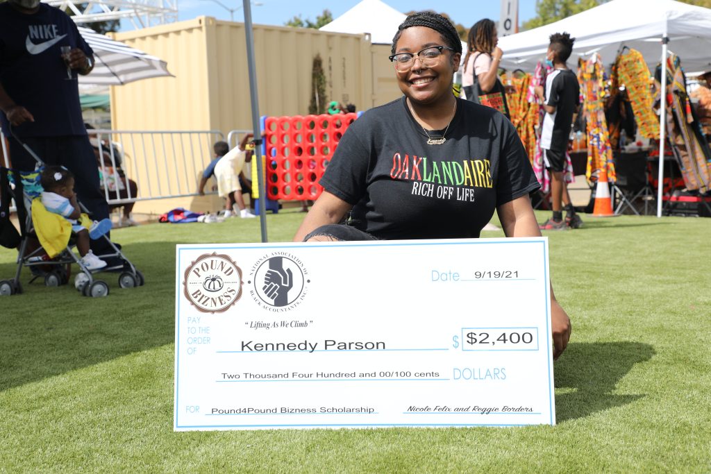 An African American woman holds a large check