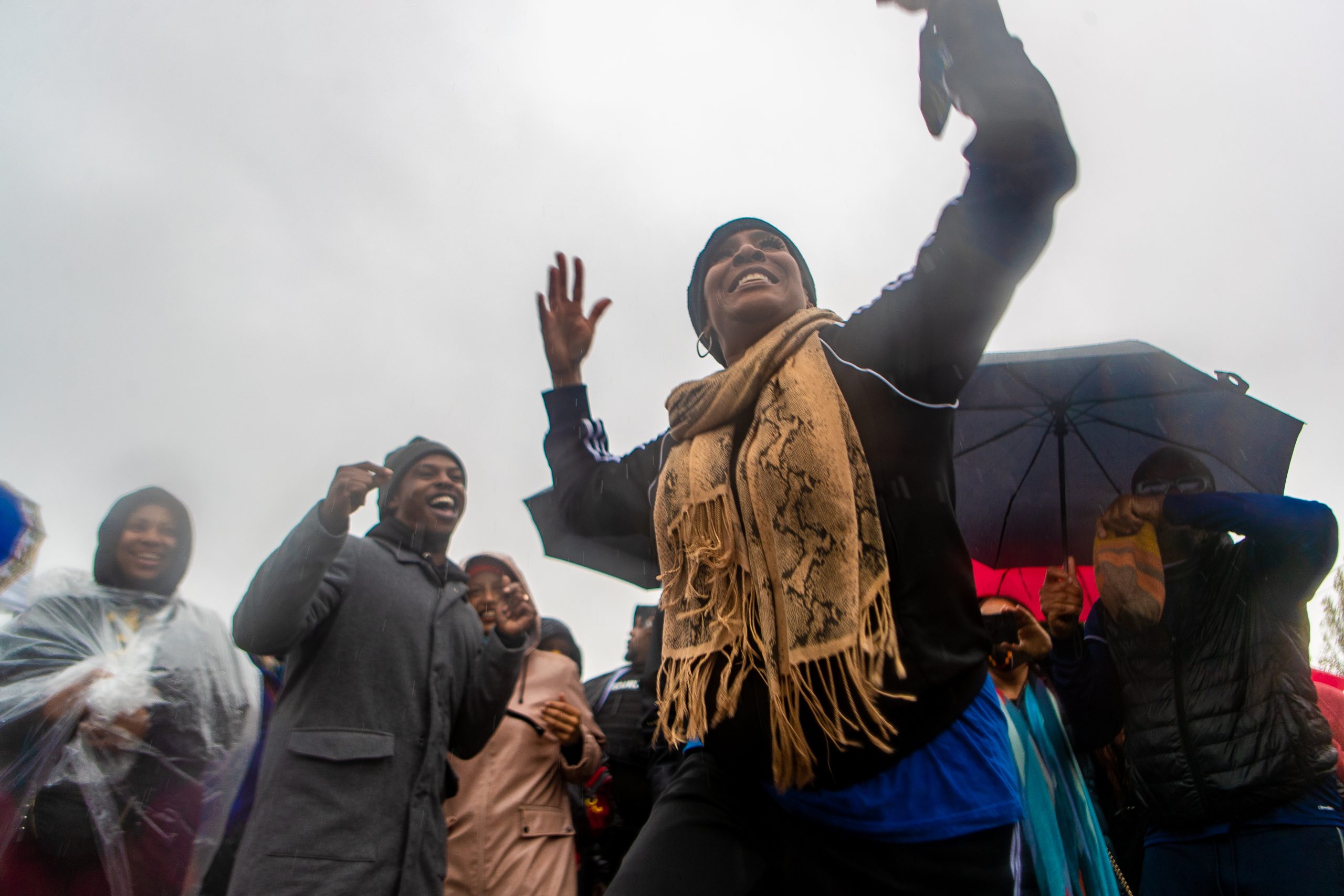 An African American woman dances joyfully against an overcast backdrop and in the rain