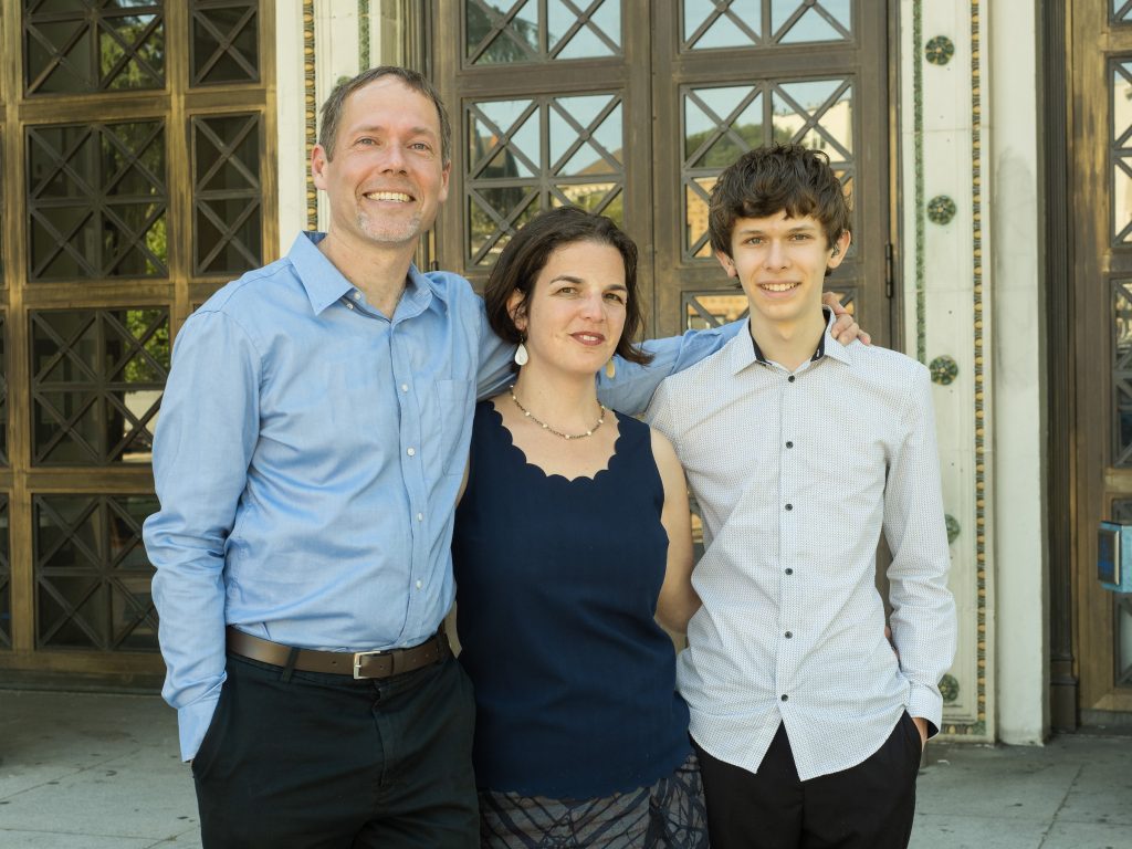 A man, woman, and teen son stand in front of an Oakland historic-looking building.