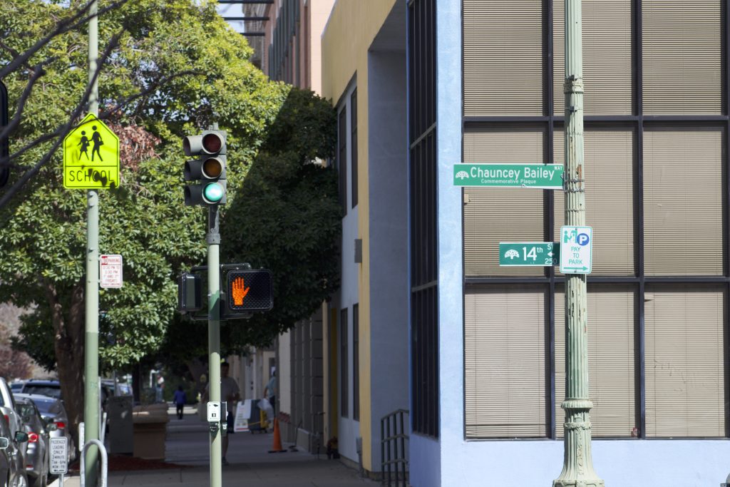 street signs outside a building, with one saying "Chauncey Bailey Way"