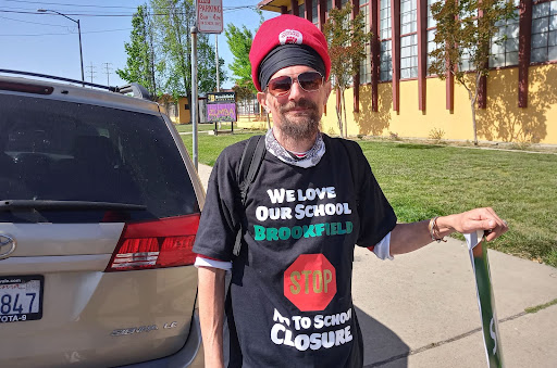 A man with red and black head wrap wears black t-shirt that says we love our brookfield