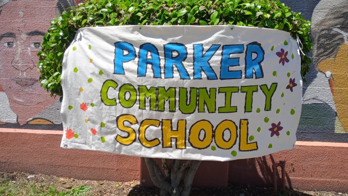 A handmade banner on white butcher paper says Parker Community School