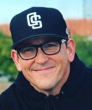 A man wearing black cap and glasses smiles for camera