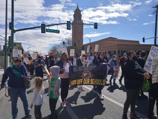 Image of a crowd holding signs walking down the street.