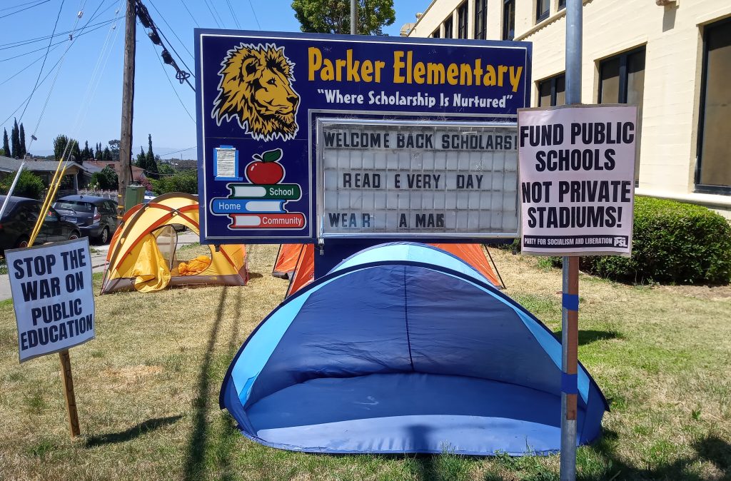 a blue tent in front of a school marquee that says "Parker school" on a sunny day