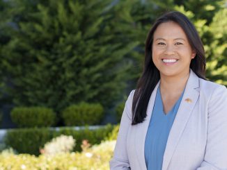 Image of Hmong American woman wearing off white blazer smiling outside