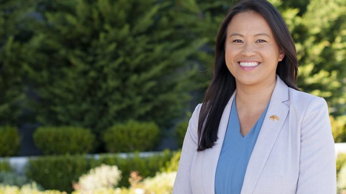 Image of Hmong American woman wearing off white blazer smiling outside