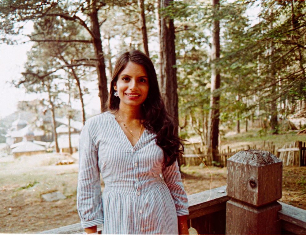 Image of a woman with brown hair wearing a shirt-dress in the woods