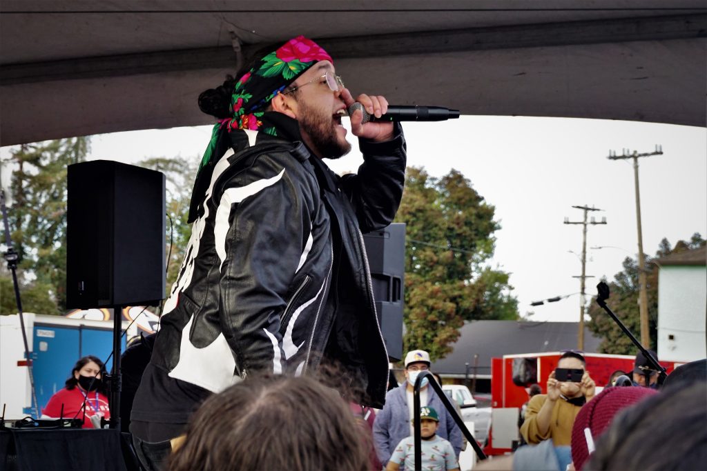 A member of an Indigenous rap group sings into a mic