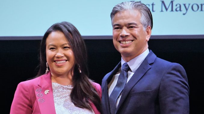 A Hmong American woman stands next to a Filipino American man on stage at the inauguration ceremony