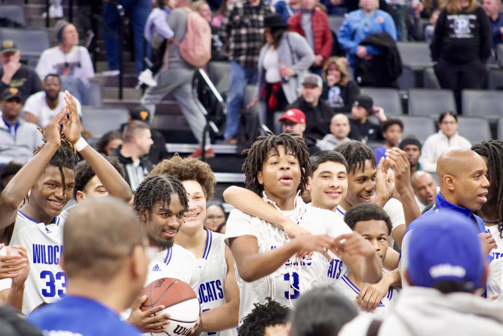 A group of mostly African American boys cheer and celebrate after winning a state title