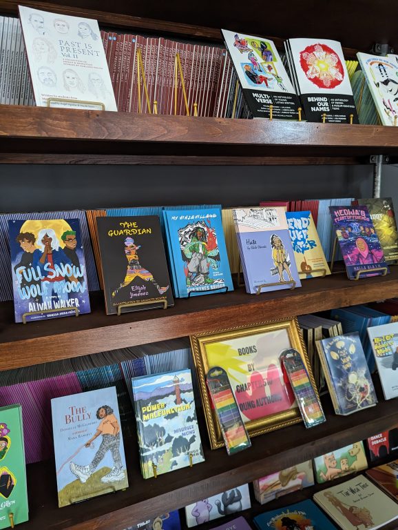 A wooden bookshelf inside a bookstore in Oakland with colorful books on the shelf