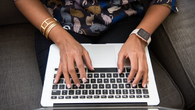 an overhead view of a woman's hands typing on a laptop