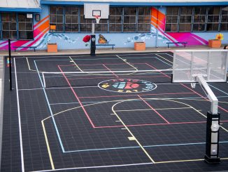 An aerial photo of a black basketball court that says "Eat. Learn. Play." in colorful font
