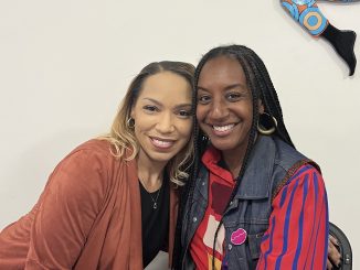 Two African American women hug next to each other and smile for a photo