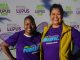 An African American woman and Latina woman stand next to each other during a charity walk wearing purple t-shirts
