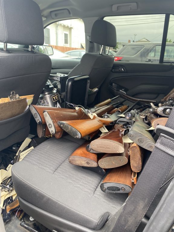 inside a police car, you see a bunch of metal and wooden handled rifles in the backseat