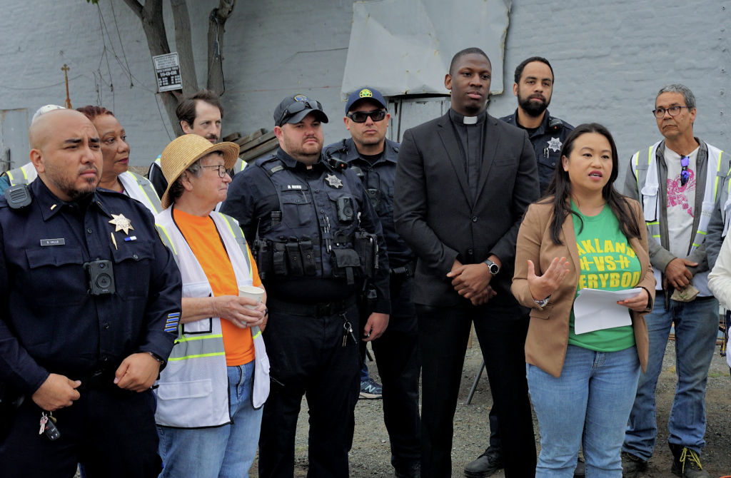 a group of police, a Hmong American woman mayor, and volunteers stand for a press conference