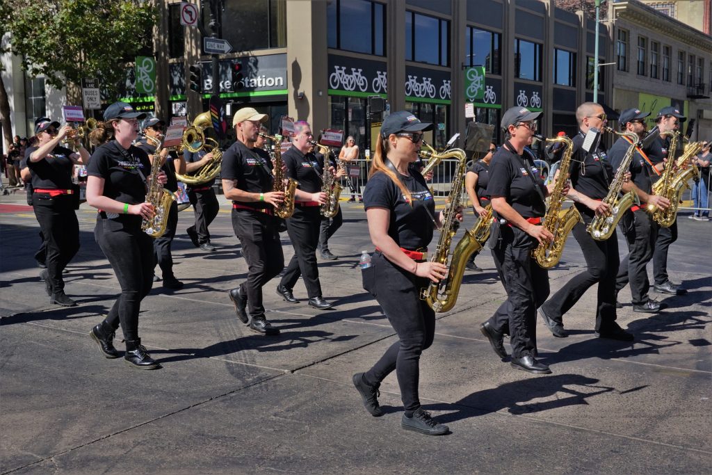 a marching band wearing black caps and black t-shirts walk in parade