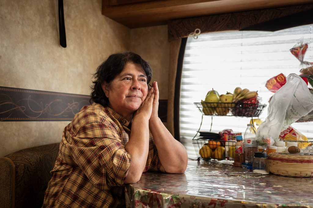 A Guatemalan woman sits at her kitchen table with her hands by her face