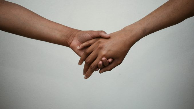 two brown hands holding hands with white background