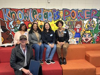 five people sit in front of an indoor mural that says "knowledge is power"
