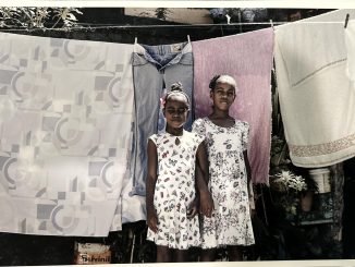 Two girls in El Salvador stand in front of a clothing line